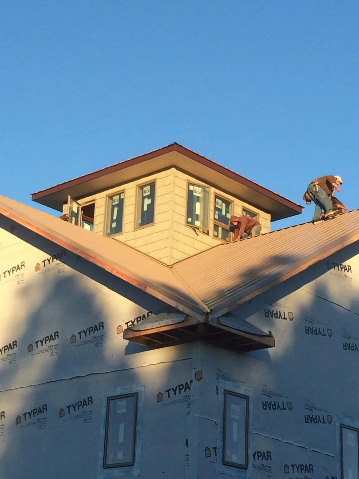 Roofers working around a rooftop cupola on a new metal roof at sunset — Roof Waterproofing in Memphis by Roofing Brothers